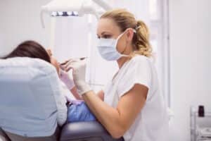 Medic stomatolog realizand tratament pentru abces dentar unui pacient, in cabinet