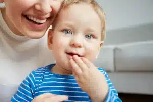 Mamă care își ține în brațe bebelușul de un an, în perioada erupției primilor dinți de lapte