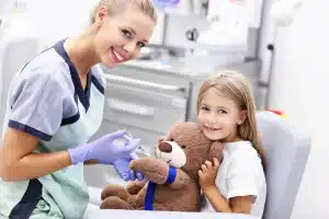 Medic și copil, în cabinetul stomatologic, cu un ursuleț de plus