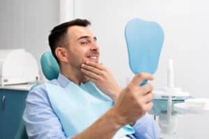 Barbat care verifica in oglinda ca nu mai are umflatura dupa implant dentar