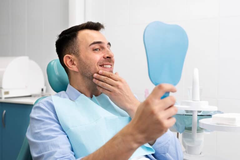 Barbat care verifica in oglinda ca nu mai are umflatura dupa implant dentar
