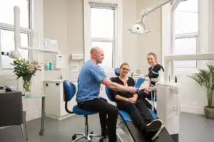Femeie la dentist, zambind dupa interventia cu implant dentar