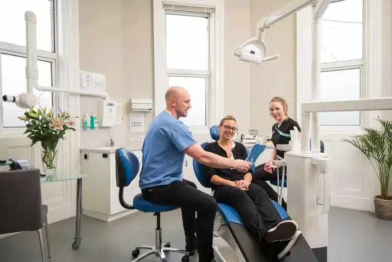 Femeie la dentist, zambind dupa interventia cu implant dentar