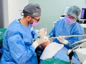 Dr. Alexandru Ciucu realizand o interventie dinti ficsi, alaturi de asistenta, intr-un cabinet modern Dental Elite