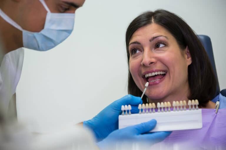 Femeie la dentist in timpul alegerii culorii pentru dintii din zirconiu