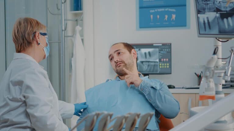 Pacient la dentist, care arata ca i se vede implantul dentar