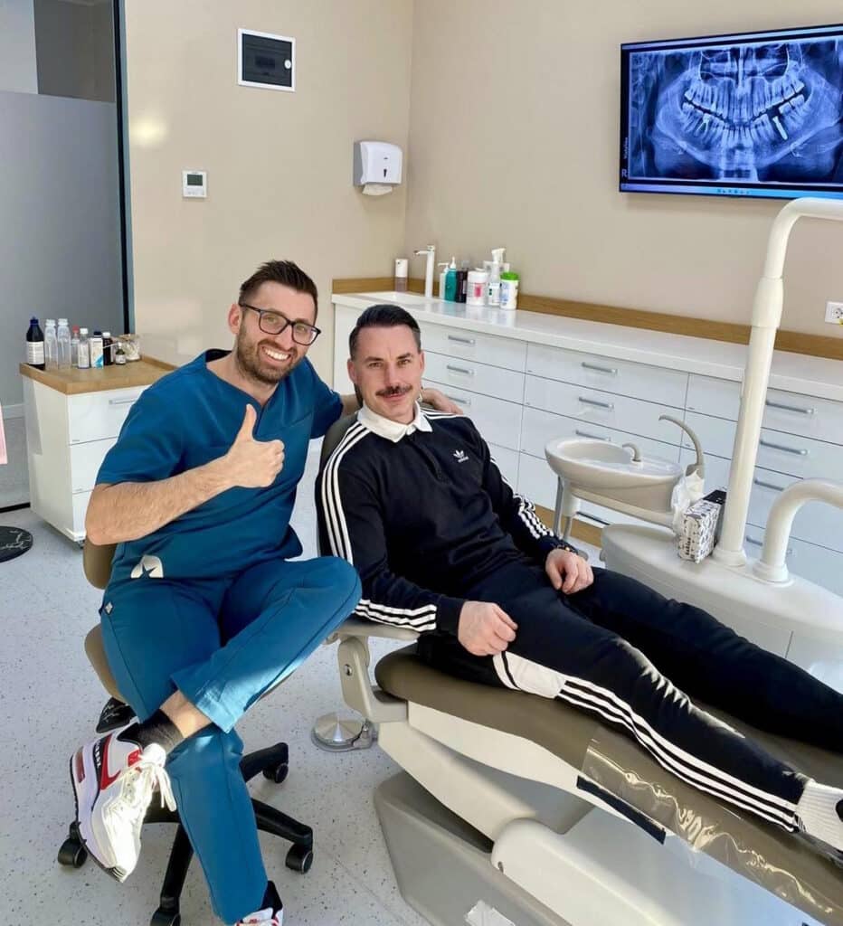 Dr. Alexandru Ciucu si pacient, zambind, la consultatie, cu radiografia dentara alaturi