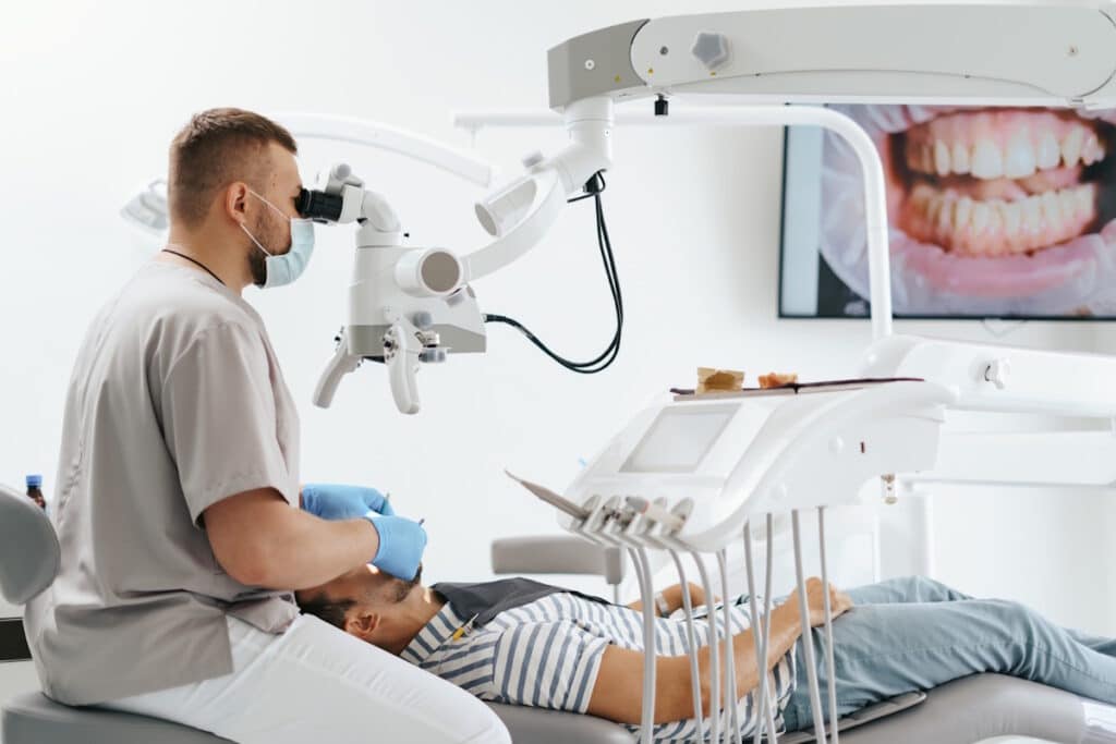 Medic stomatolog care efectueaza un retratament endodontic la microscop