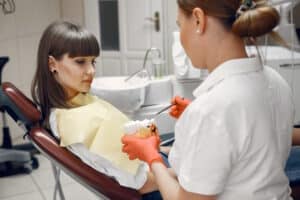Medic care ii arata pacientei nervul dentar, pe un mulaj, in cabinet