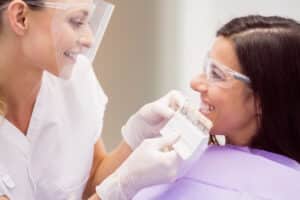 Femeie la dentist, in timpul testului de culoare pentru dintii provizorii