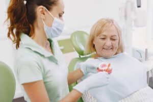 Medic stomatolog explicand pacientei igiena orala corecta dupa implant dentar